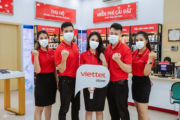 Nhân viên cửa hàng mặc đồng phục đỏ đứng tại quầy giao dịch