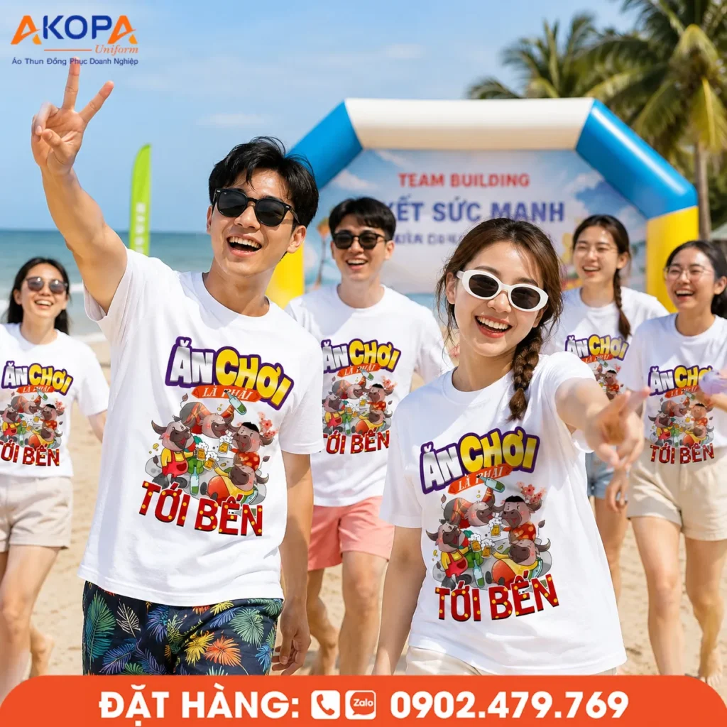 Áo phông team building trắng in hình theo yêu cầu, nhóm bạn trẻ tham gia hoạt động gắn kết trên bãi biển, thiết kế nổi bật, chất liệu thoáng mát và năng động.