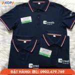 Áo polo Mcredit màu xanh navy được thiết kế theo phong cách chuyên nghiệp với logo thương hiệu trước ngực và chi tiết bo sọc đỏ trắng nổi bật ở cổ và tay áo