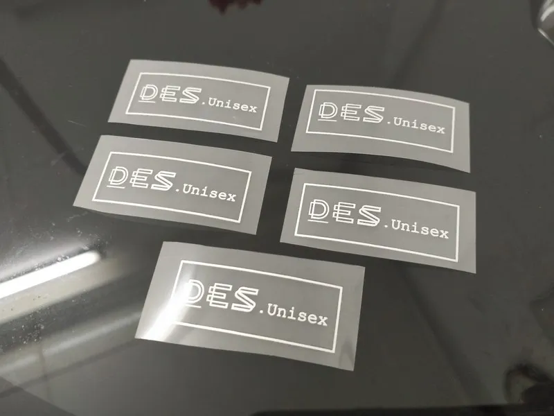 Hình ảnh decal chuyển nhiệt logo DES.Unisex được sản xuất trên film PET chất lượng cao, đường nét sắc nét, màu in đồng đều và sẵn sàng ép nhiệt lên áo thun, áo polo hoặc đồng phục thương hiệu. Công nghệ decal chuyển nhiệt phù hợp với nhu cầu in logo, tên riêng và hình ảnh chi tiết trên nhiều chất liệu vải khác nhau.