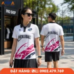 Mẫu áo Pickleball phối trắng – hồng – đen với họa tiết cách điệu hiện đại, tạo điểm nhấn năng động và cá tính. Chất liệu vải thể thao co giãn 4 chiều, thoáng khí, thấm hút mồ hôi tốt, phù hợp cho thi đấu, luyện tập và làm đồng phục Pickleball chuyên nghiệp.