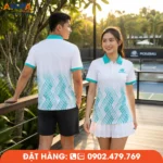 Mẫu áo đồng phục Pickleball có cổ sử dụng tông trắng phối xanh ngọc cùng họa tiết ziczac hiện đại, tạo cảm giác trẻ trung và nổi bật. Bối cảnh trên lối đi gỗ hướng ra sân Pickleball giúp thể hiện rõ vẻ đẹp của mẫu áo trong không gian nghỉ dưỡng và thi đấu chuyên nghiệp.