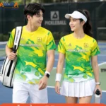 Áo đồng phục pickleball cổ tròn phối tông vàng và xanh lá nổi bật với họa tiết trừu tượng độc đáo, chất liệu co giãn, thoáng khí, thích hợp cho luyện tập, thi đấu và hoạt động câu lạc bộ.
