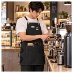 Nam barista đeo tạp dề canvas dây chéo màu đen khi pha cà phê tại quán – AKOPA